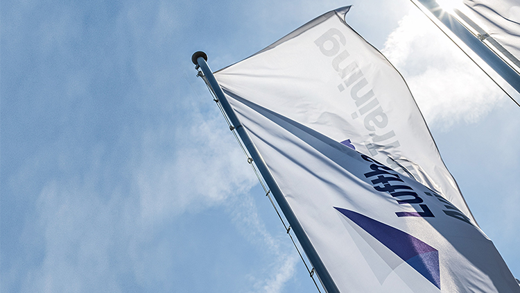 A flag with the logo of Lufthansa Aviation Training blows in the wind